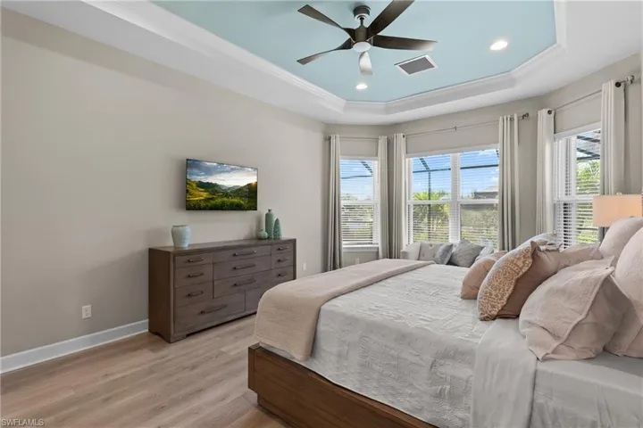 Bedroom featuring a tray ceiling, baseboards, visible vents, and light wood-style floors