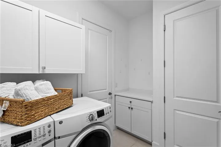 Laundry room with washer and dryer, cabinet space, and light tile patterned floors