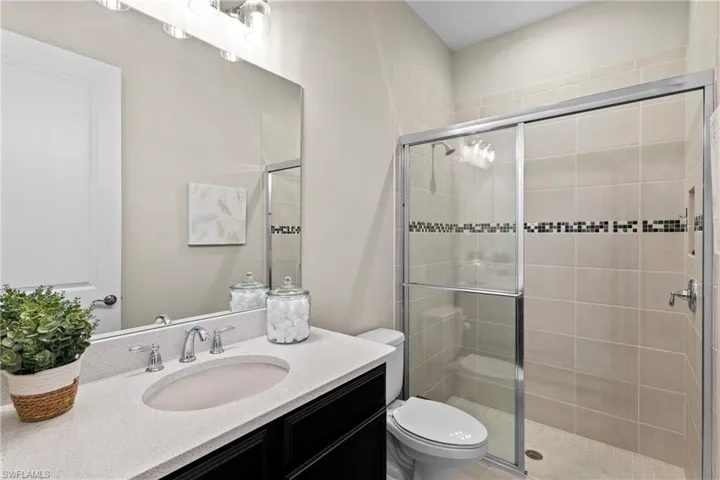 Full bath featuring toilet, vanity, and a shower stall