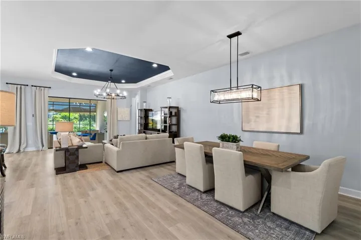 Dining area with light wood-style flooring, a notable chandelier, a tray ceiling, and visible vents