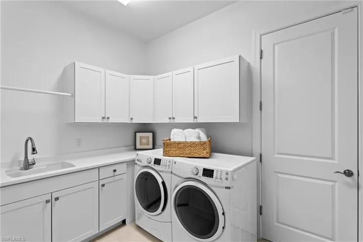 Laundry room featuring washer and clothes dryer, cabinet space, and a sink
