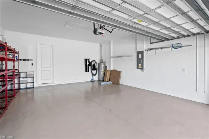 Garage featuring a garage door opener, gas water heater, and electric panel