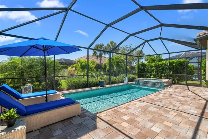 View of pool featuring a patio, a pool with connected hot tub, and glass enclosure