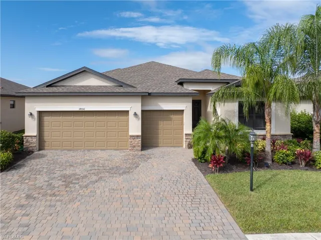 View of front of property featuring stone siding, decorative driveway, stucco siding, and an attached garage