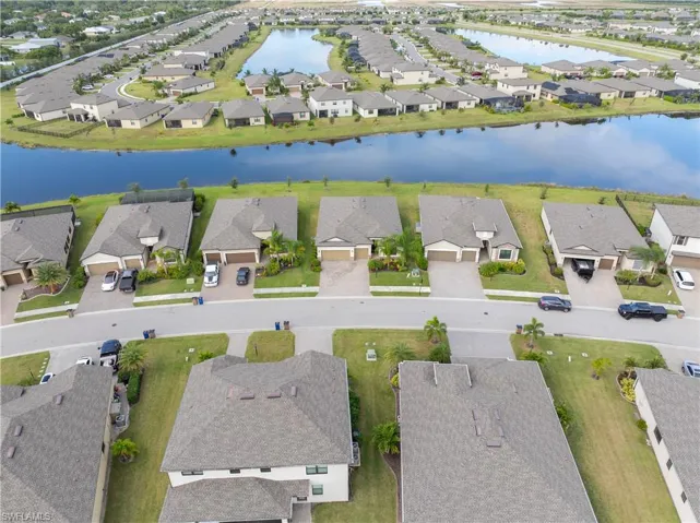 Aerial view of property and surrounding area featuring nearby suburban area and a large body of water