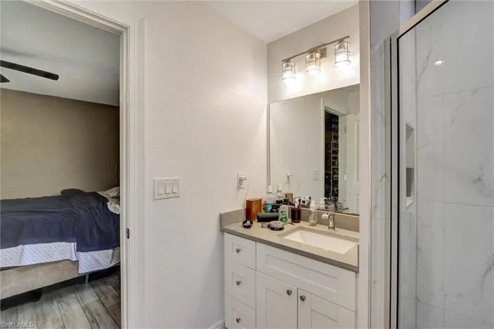 Bathroom vanity featuring an integrated sink, light-colored countertop, and storage cabinetry with brushed nickel hardware