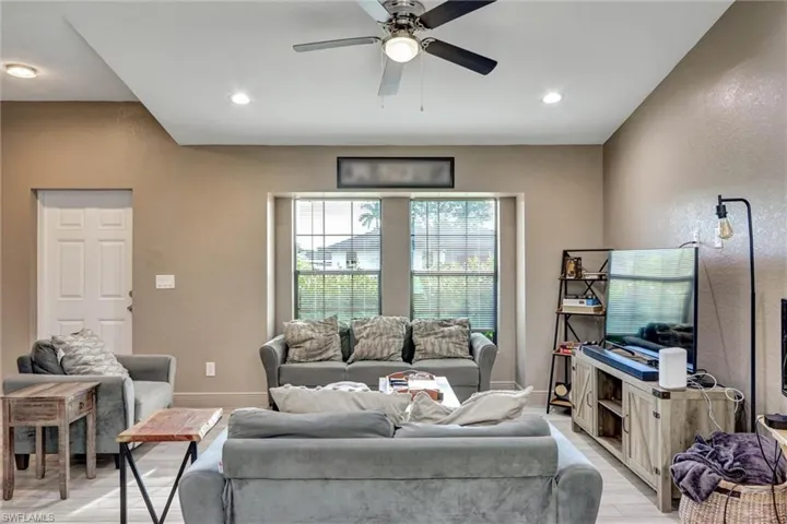 Spacious living area featuring a tray ceiling with recessed lighting and a ceiling fan