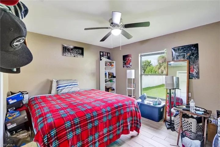 Room featuring textured walls, a ceiling fan with integrated lighting, and wood-finish flooring