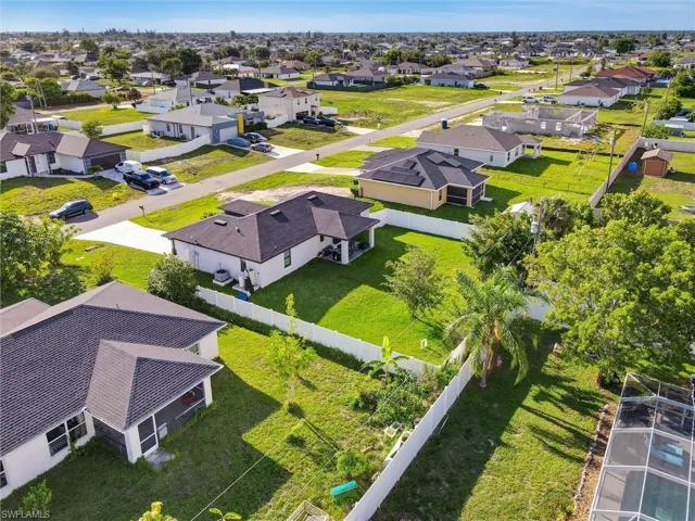 Aerial perspective showcasing residential homes with dark shingle roofs and white or light-colored exteriors