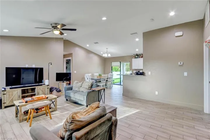 Open-concept living area featuring wood-finish flooring, recessed lighting, and a vaulted ceiling