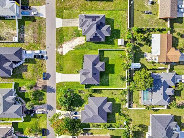 Residential properties featuring concrete driveways, mature landscaping, and fenced backyards