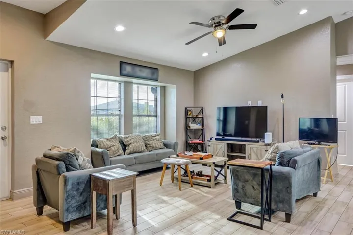 Spacious living area featuring wood-finish flooring, recessed lighting, and a ceiling fan with integrated light