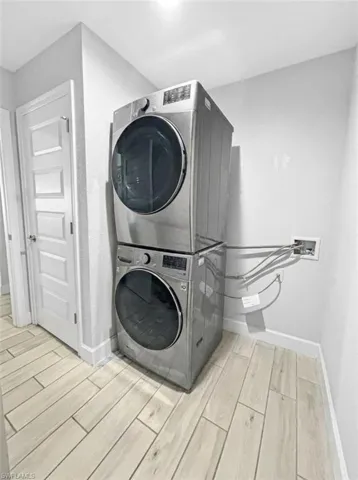 Laundry area with wood finish floors and stacked washer and clothes dryer