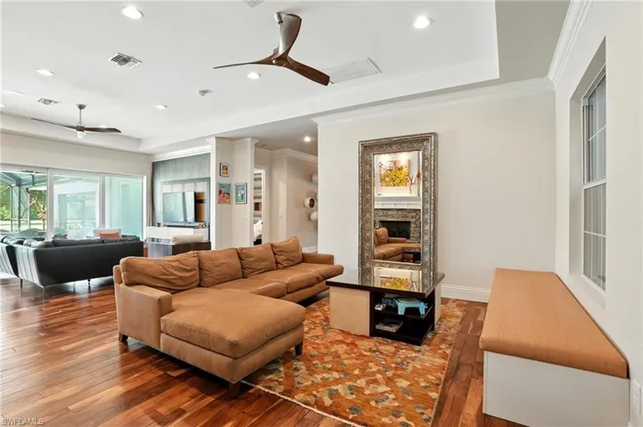 Living room featuring ceiling fan, a raised ceiling, hardwood / wood-style floors, recessed lighting, and ornamental molding - Virtually Edited Image