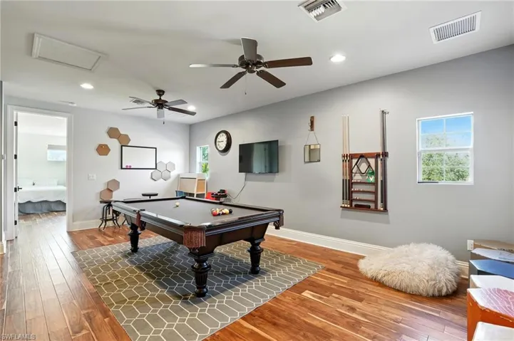 Rec room with wood-type flooring, ceiling fan, recessed lighting, billiards table, and attic access - Virtually Edited Image
