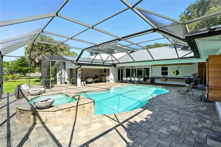 View of swimming pool featuring a patio area, a lanai, a sunroom, a pool with connected hot tub, and ceiling fan
