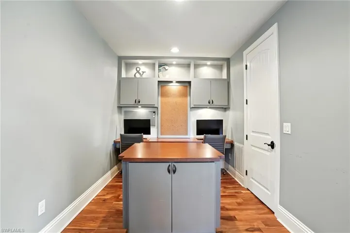 Gray cabinets, an office area, dark wood-type flooring, a center island, and recessed lighting