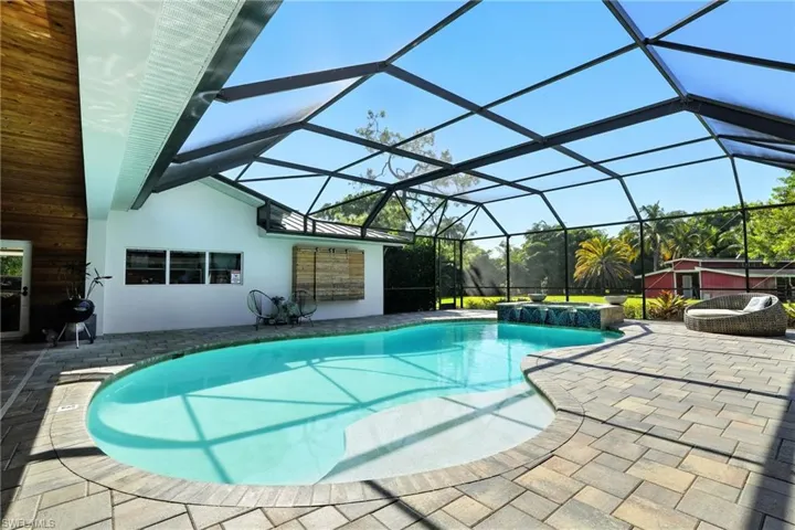 Swimming pool featuring a patio, glass enclosure, and a sunroom - Virtually Edited Image