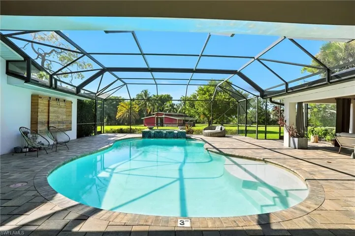 View of swimming pool with a patio area, a sunroom, a pool with connected hot tub, and a lanai - Virtually Edited Image