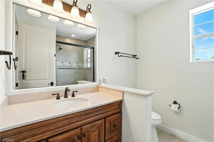 Full bathroom featuring a stall shower, vanity, and light tile patterned flooring - Virtually Edited Image
