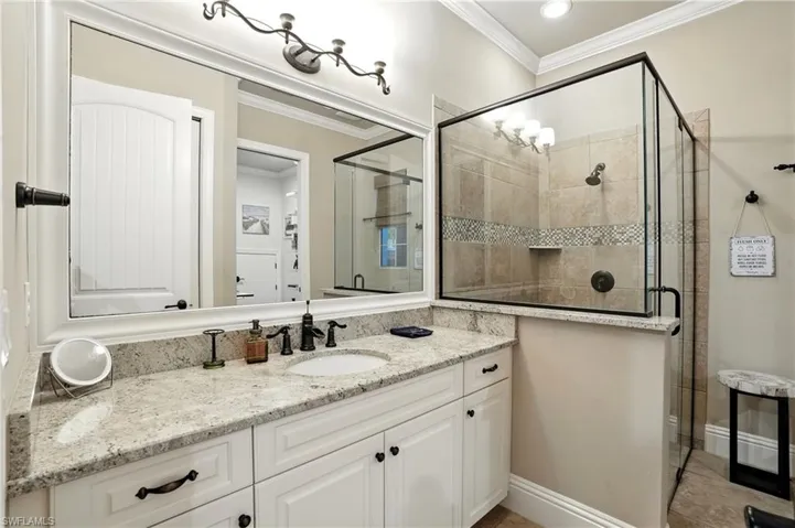 Bathroom featuring vanity, a stall shower, and crown molding - Virtually Edited Image