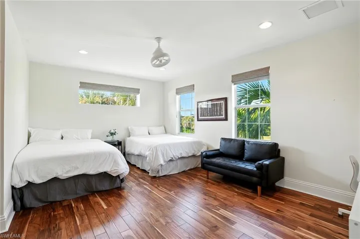 Bedroom featuring multiple windows, wood-type flooring, and recessed lighting - Virtually Edited Image