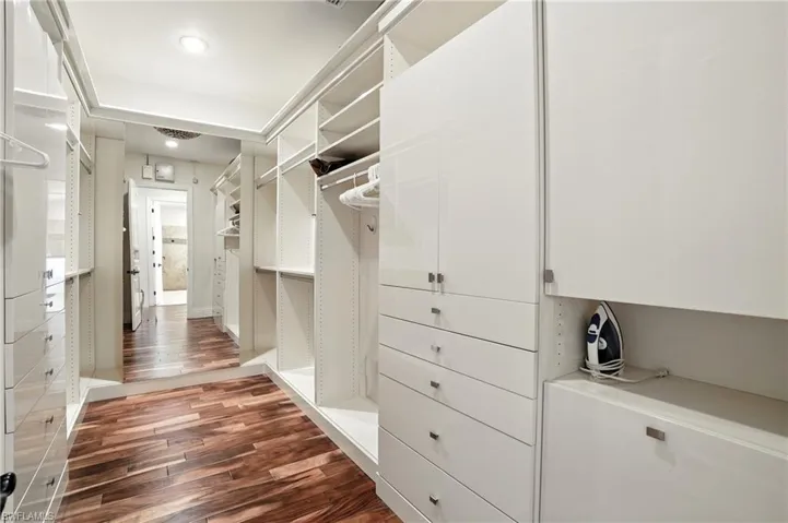 Walk in closet featuring dark wood finished floors - Virtually Edited Image