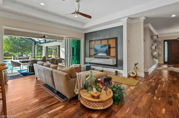 Living room with a sunroom, wood finished floors, recessed lighting, a raised ceiling, and ceiling fan - Virtually Edited Image