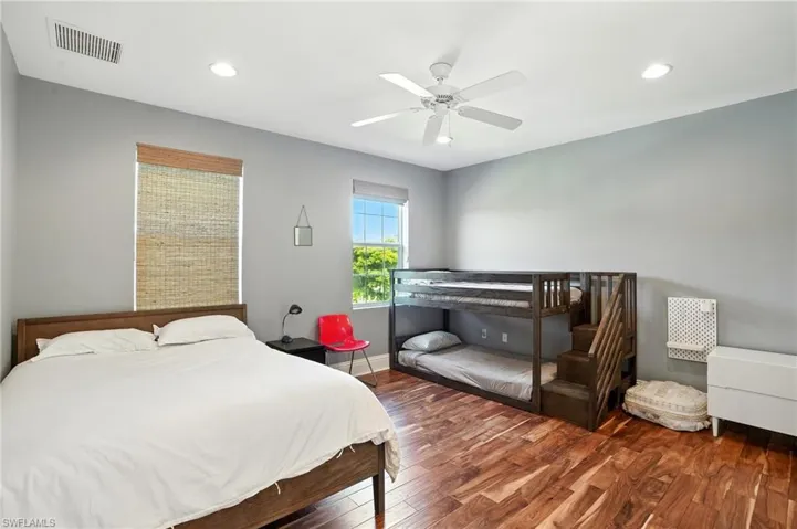 Bedroom with wood finished floors, recessed lighting, and a ceiling fan - Virtually Edited Image