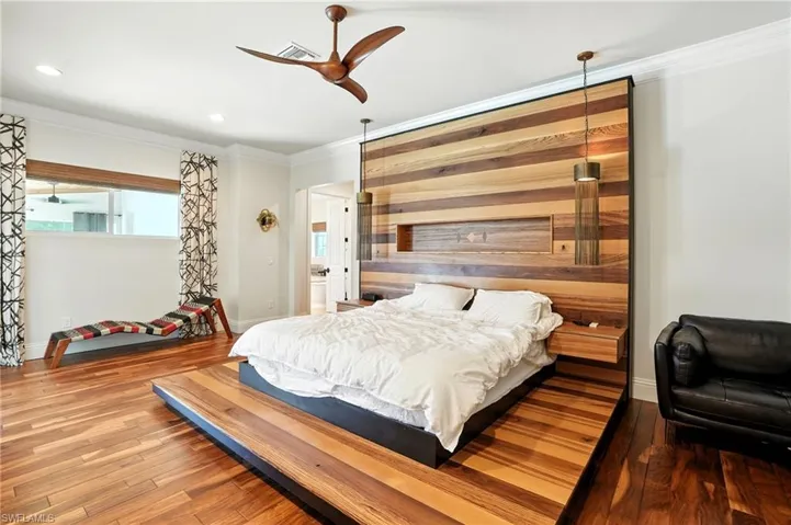 Bedroom featuring crown molding, wood finished floors, ceiling fan, wooden walls, and recessed lighting - Virtually Edited Image