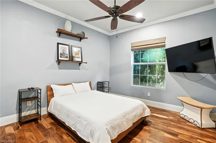 Bedroom featuring crown molding, wood finished floors, a ceiling fan, and recessed lighting - Virtually Edited Image