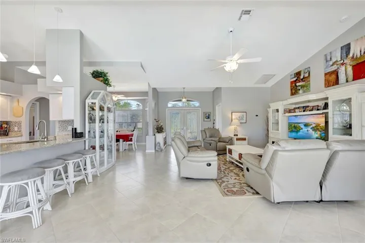 Tiled living room featuring sink, high vaulted ceiling, and ceiling fan with notable chandelier