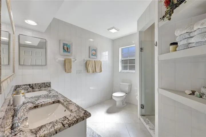 Bathroom featuring vanity, tile patterned flooring, toilet, tile walls, and an enclosed shower
