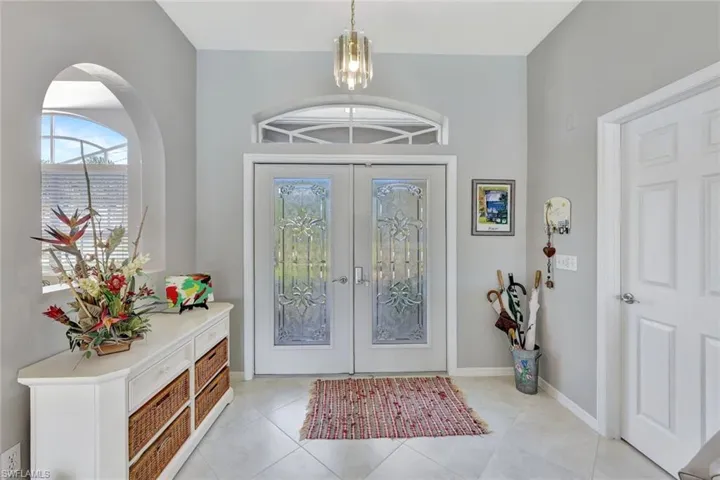Foyer featuring french doors, light tile patterned floors, and a notable chandelier