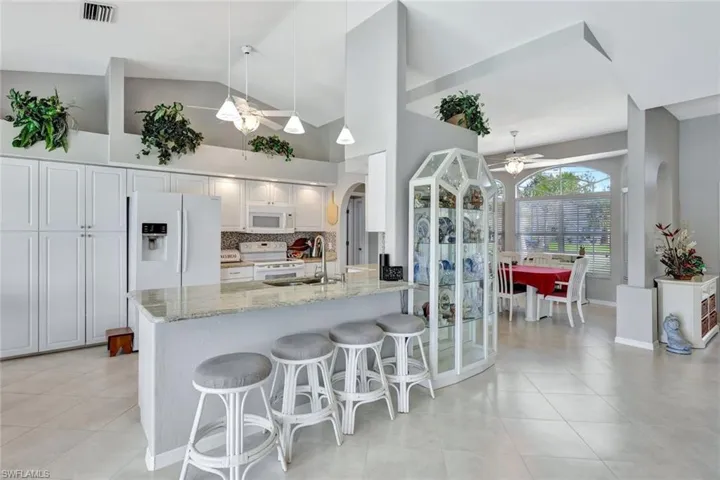 Kitchen with kitchen peninsula, white appliances, hanging light fixtures, and ceiling fan