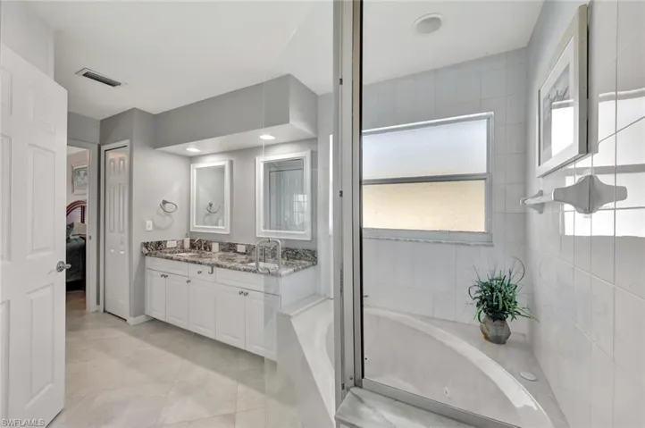 Bathroom featuring tile patterned floors, vanity, and a tub to relax in