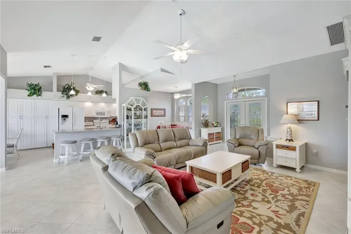 Tiled living room with ceiling fan and high vaulted ceiling