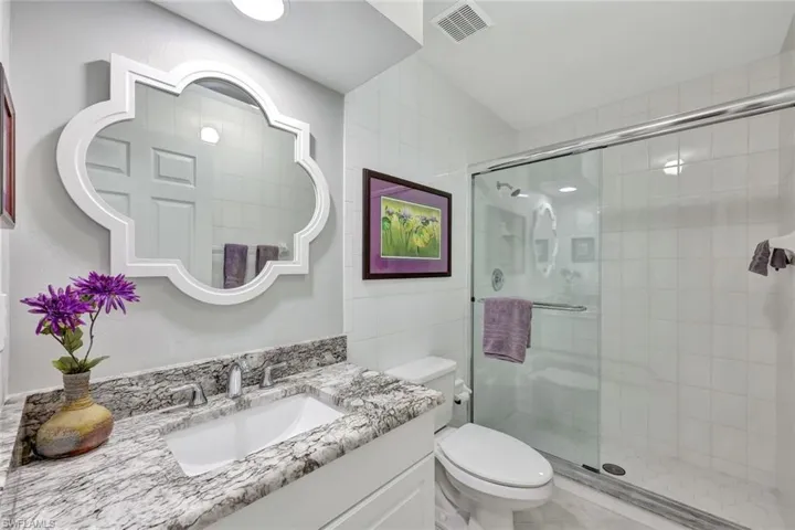 Bathroom with vanity, a shower with shower door, and toilet