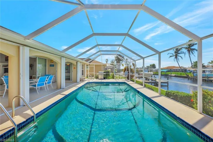 View of swimming pool featuring glass enclosure, a patio area, and a water view