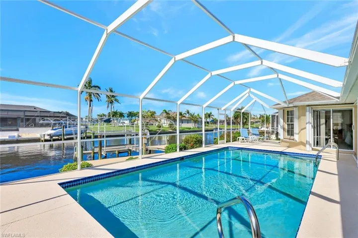 View of swimming pool featuring a dock, a water view, glass enclosure, and a patio area