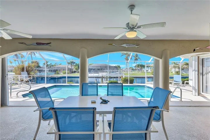 View of patio with a lanai, ceiling fan, and a water view