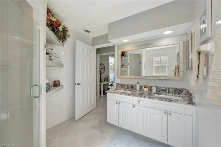 Bathroom featuring tile patterned floors, vanity, a shower with shower door, and tile walls