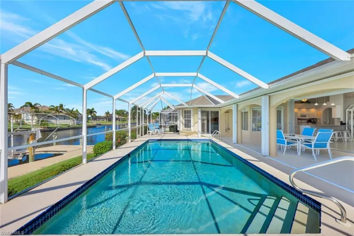View of swimming pool with a patio area, a water view, and glass enclosure