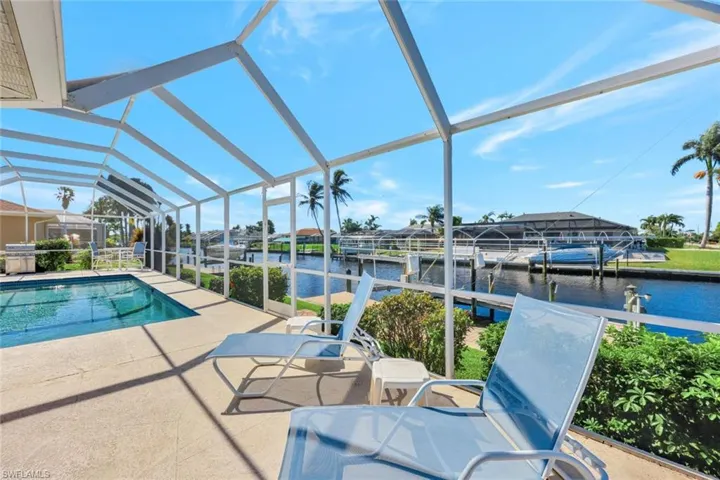 View of pool with a lanai, a patio area, a dock, and a water view