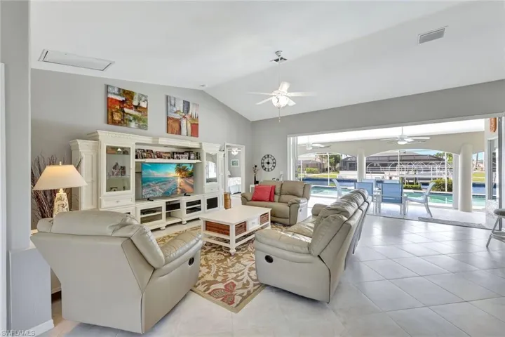 Living room featuring ceiling fan, light tile patterned floors, and lofted ceiling