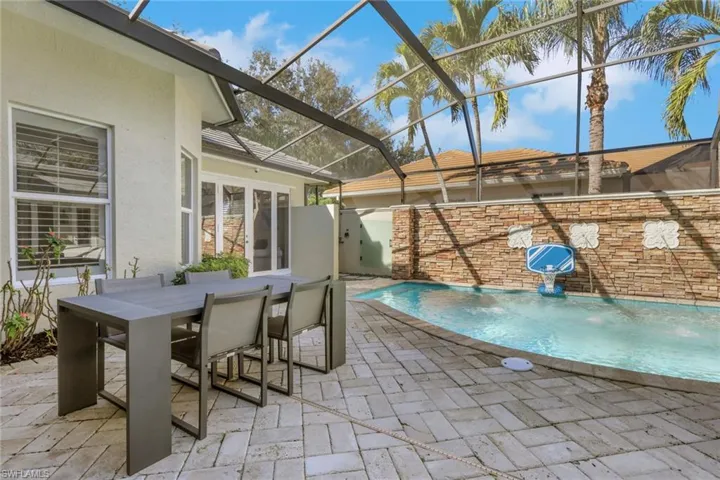 View of swimming pool featuring a patio area, a sunroom, a lanai, and outdoor dining area