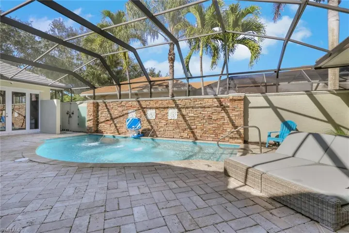 View of pool featuring a sunroom, a patio area, and glass enclosure
