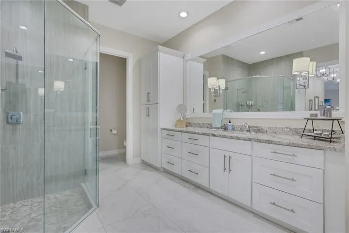 Bathroom with vanity, light marble finish floors, and a shower stall