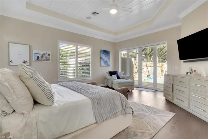 Bedroom featuring a tray ceiling, access to exterior, wood finished floors, wood ceiling, and ceiling fan