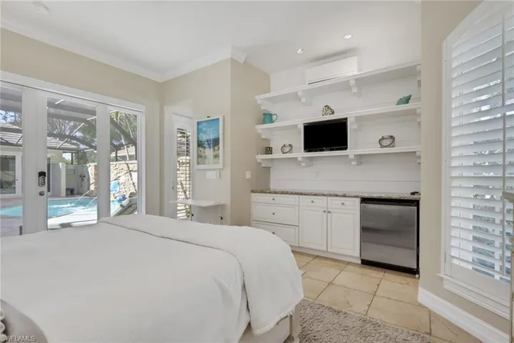Bedroom featuring multiple windows, access to outside, stainless steel fridge, a wall unit AC, and crown molding